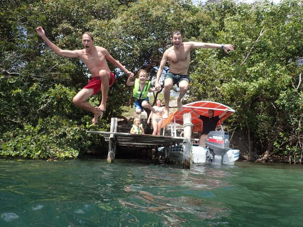 two men and small boy jumping into cenote