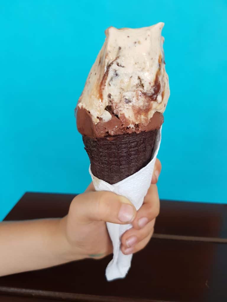 best ice cream in Merida. Chocolate ice cream in choc con being held against blue background by child's hand