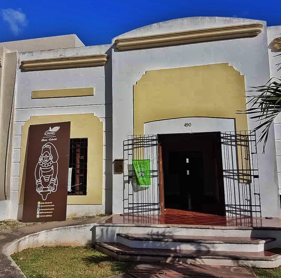 white and yellow building with Maya style brown sign otside