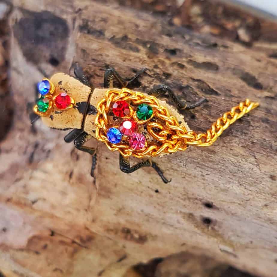 small beetle with gem stones glued to its back and a piece of chain too