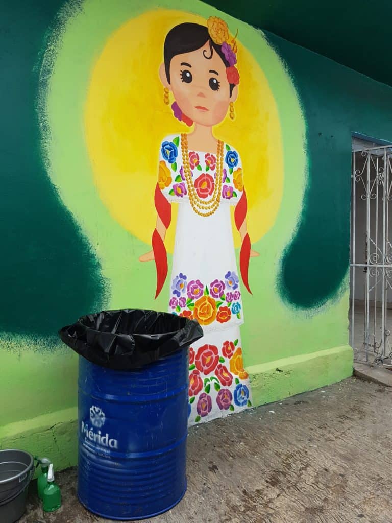 cartoon traditionally dressed woman painted on a green wall. yellow sun behind her