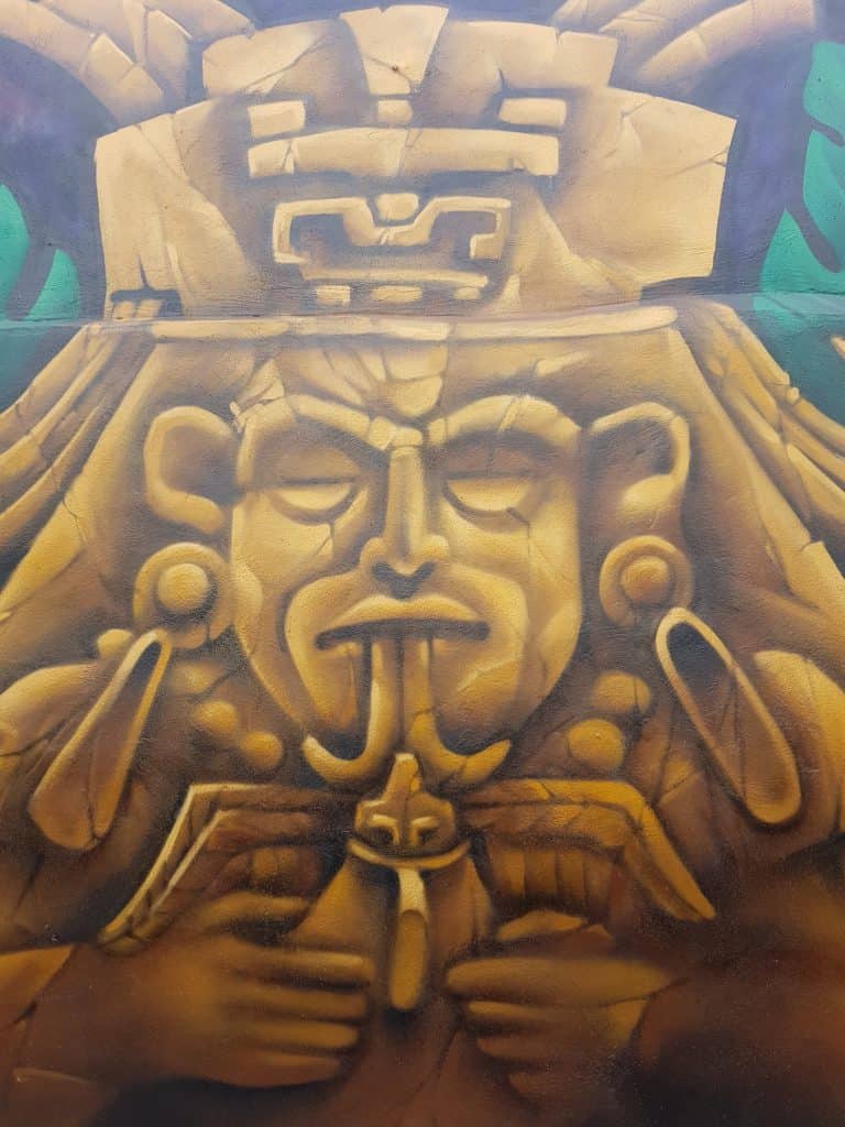 mural of a traditional Maya statue. Gold