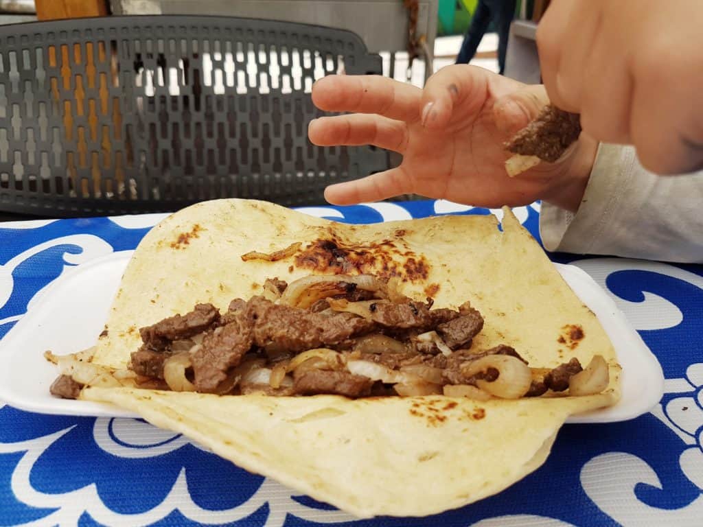 close up of a taco, small child hand taking piece of meat