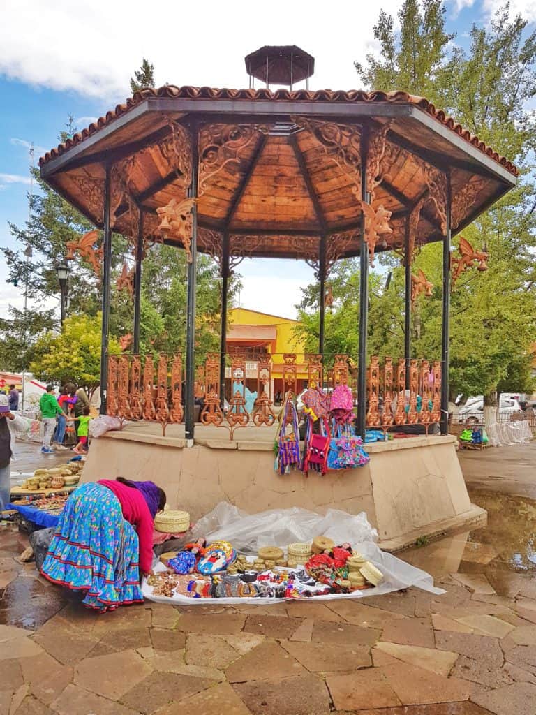 gazebo in tow square, woman bending down over her mat of souvenirs for sale