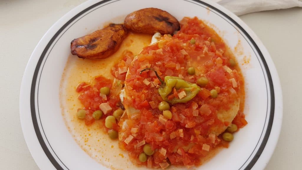 plate of huevos motuleños .- eggs covered in tomato salad