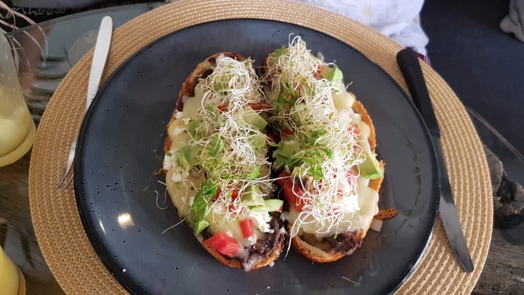 two pieces of sourdough with refried beans, cheese and salad (molletes)