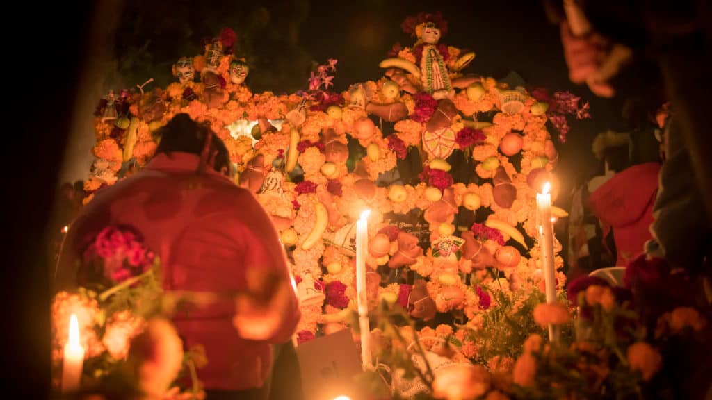 person in front of altar made of flowers and candles