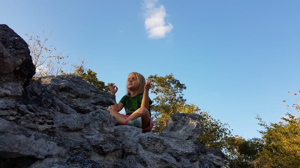 child on rocks in meditation pose