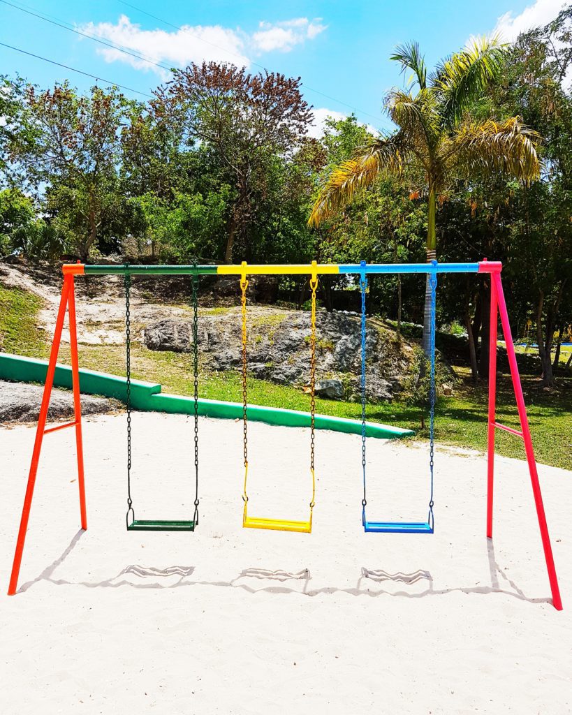 colourful metal swing set, one green, one yellow, one blue