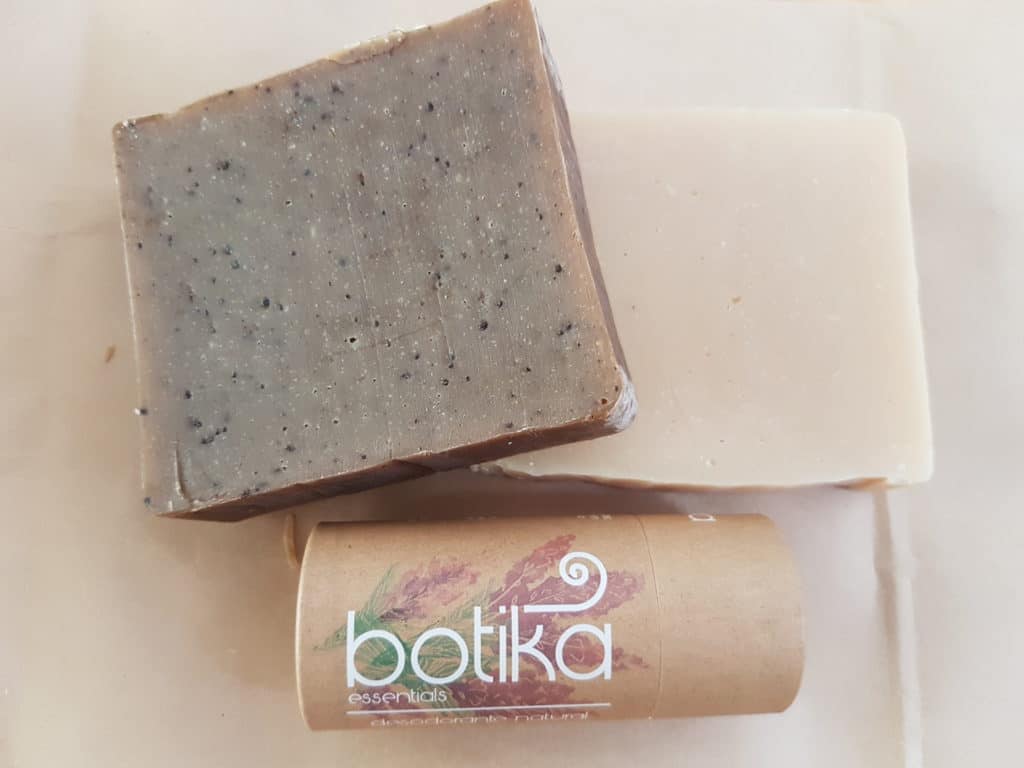 two pieces of home made soap and an organic deodorant in a brown recycled package tube. Says botika on it in white