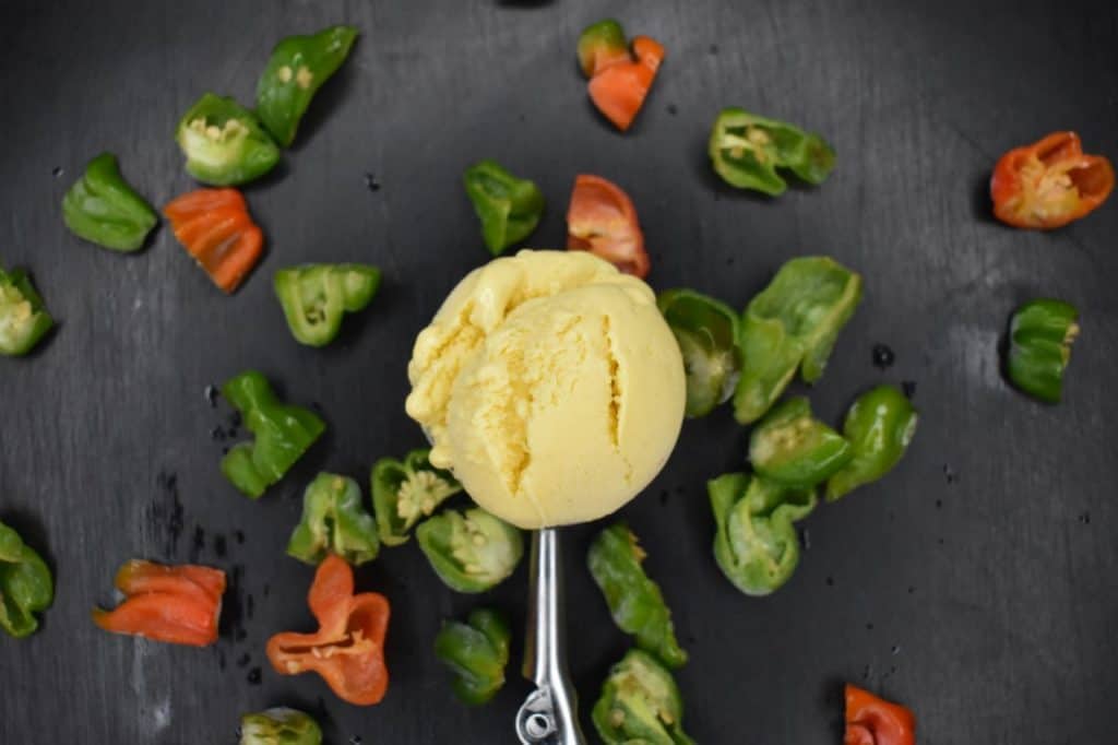 ice cream on a spoon over a tray of cut chiles