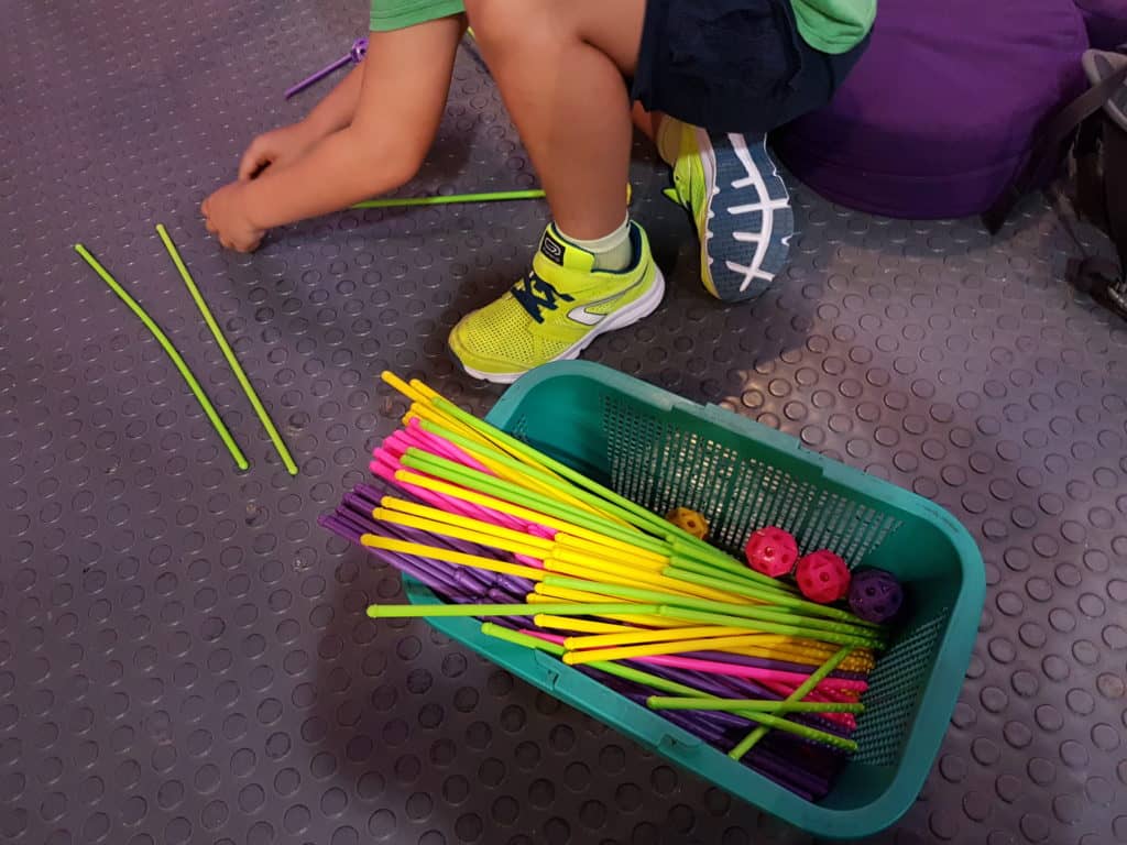 child's feet, box of mathematical straws next to him (bright colours)