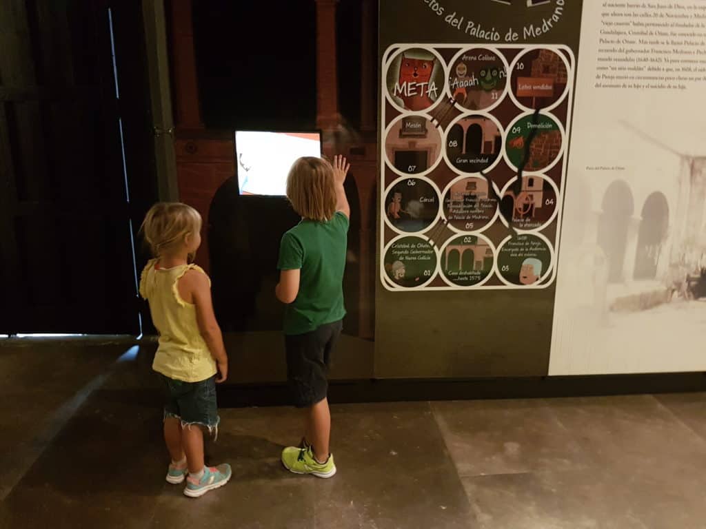 kids looking at a screen in a museum. Girl in yellow tshirt, boy in green tshirt