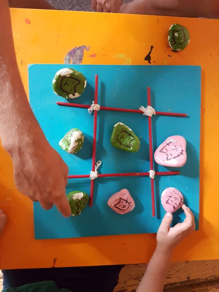tic tac toe with stones. Adult and child hand moving pieces