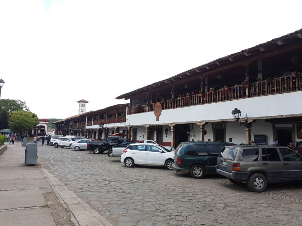 row of houses, white building, brown wooden balconies. Cars parked in a row