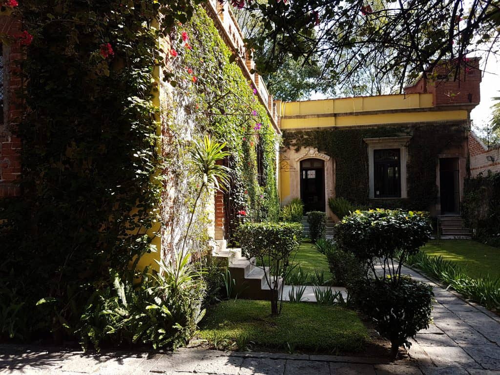 view of Trotsky's house in CDMX. Steps up, walls covered in plants.