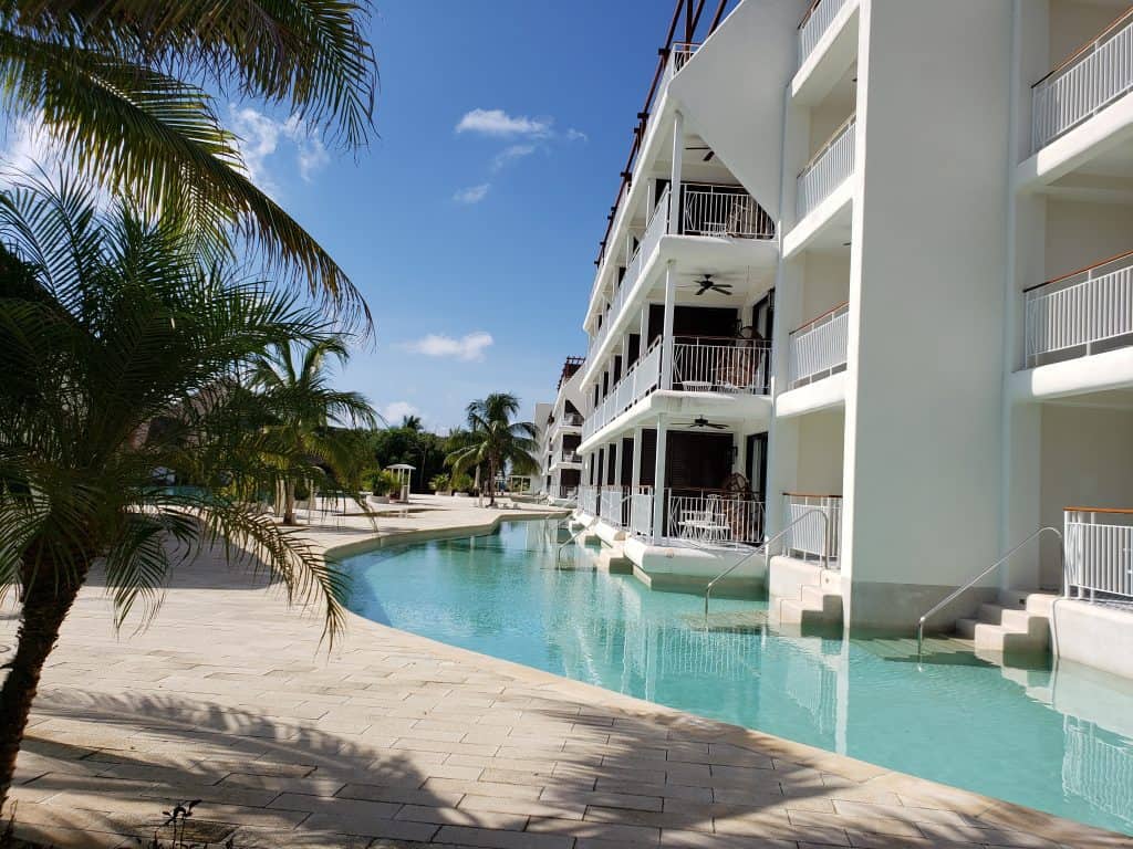 view of white hotel with balconies. pool along front of property