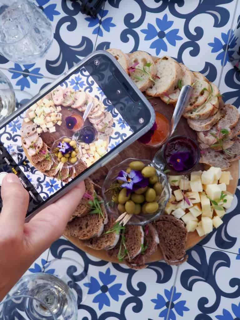 a beautiful snack plate with blue and white tiles under it. A phone being used to take a photo of the snack plate