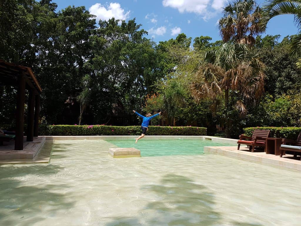 kid jumping into a pool surrounded by trees