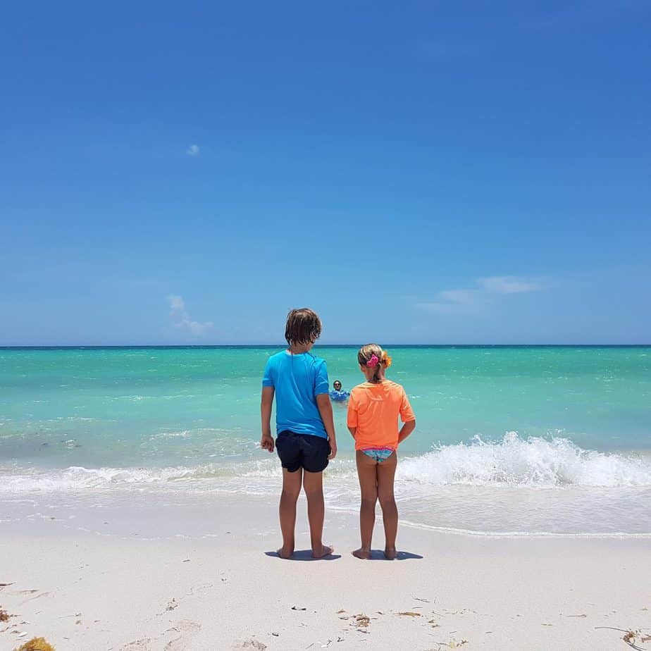 Small kids standing in front of perfect blue sea
