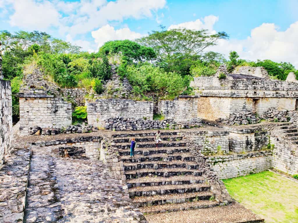 colourful photo of Maya ruin .- kid running up steps, green trees and grass all around