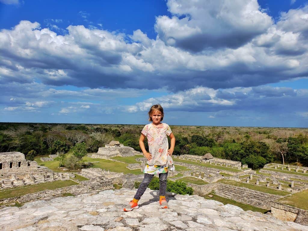 girl standing on top of pyramid, site of Mayapan in view behind her