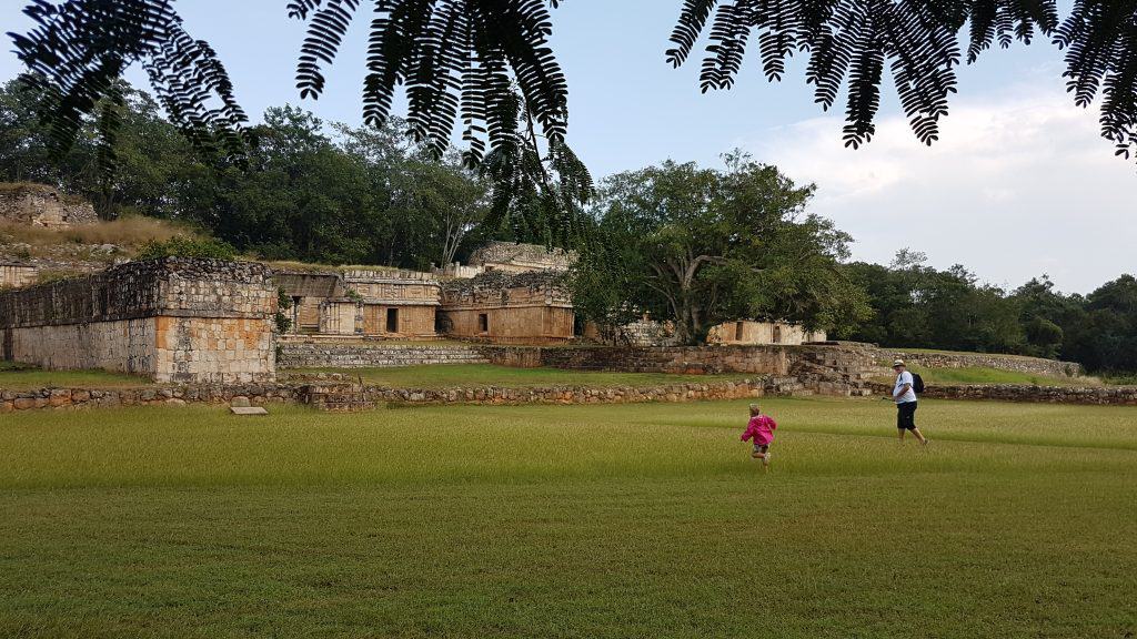 child running across grass to a maya ruin