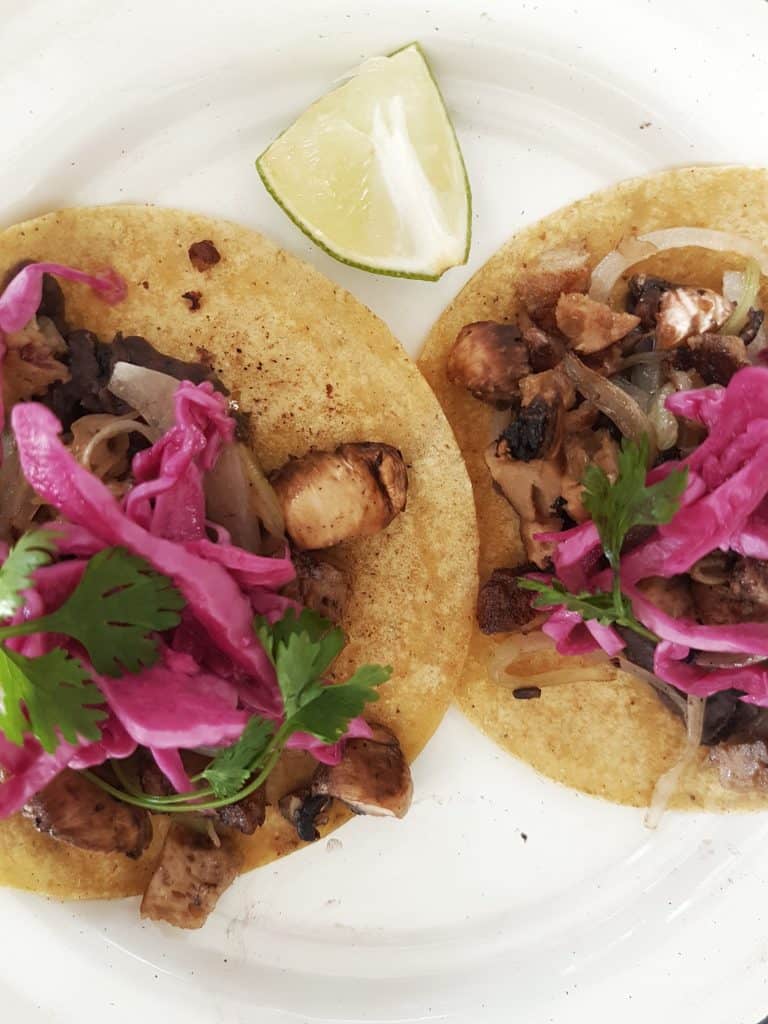 two tacos on a plate, meat, red onion, coriander leaves