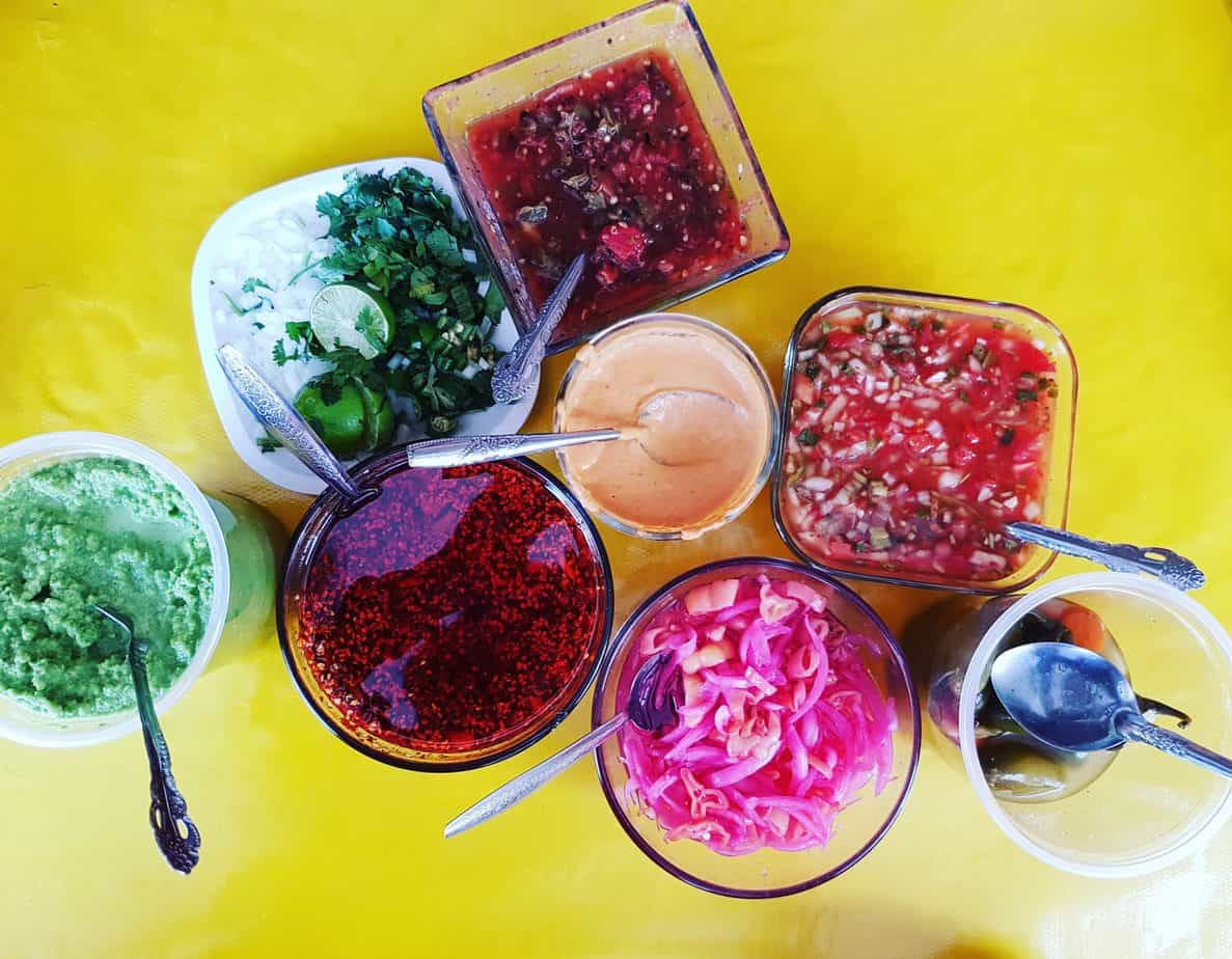 yellow table covered in colourful salsas in small bowls