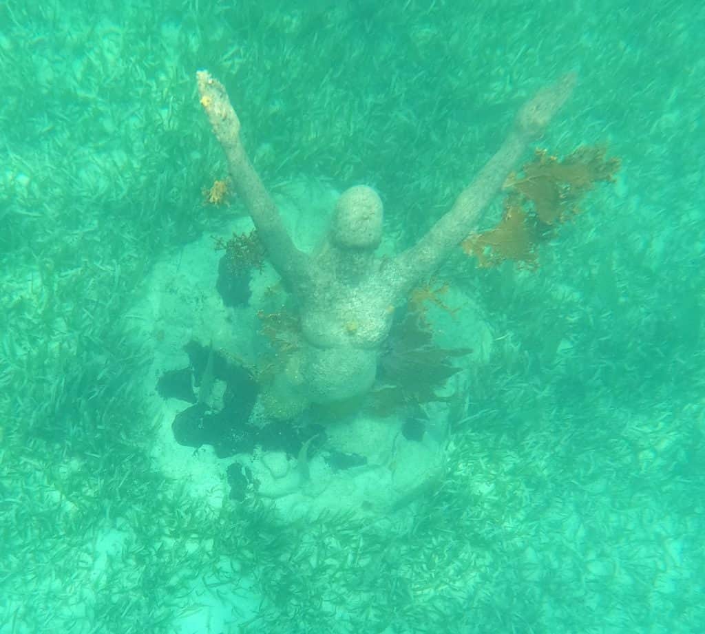very green sea water, underwater sculpture of woman holding arms up to sky