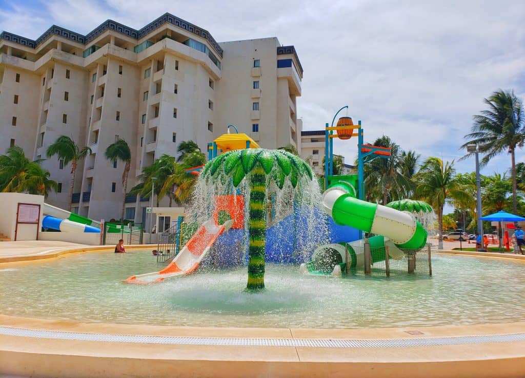 kids' water park. 2 small slides and water cascading down a fake palm tree