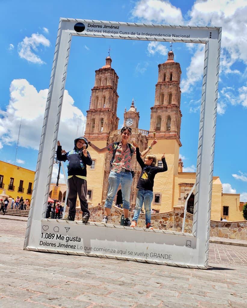 Adult and two children in an oversized photo frame. Large church behind them