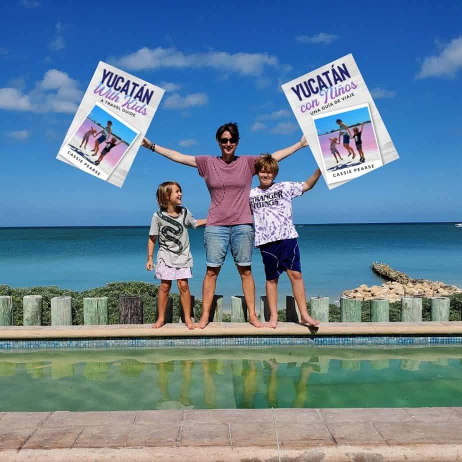 Cassie and kids standing on side of pool. Cassie holding oversized copies of her books
