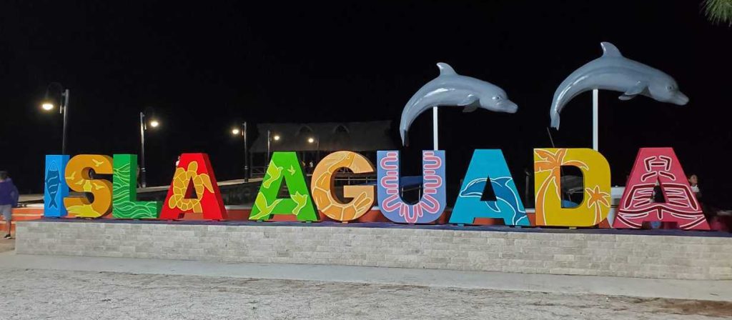 Isla Aguade large letters, dark evening, two plastic dolphins above letters