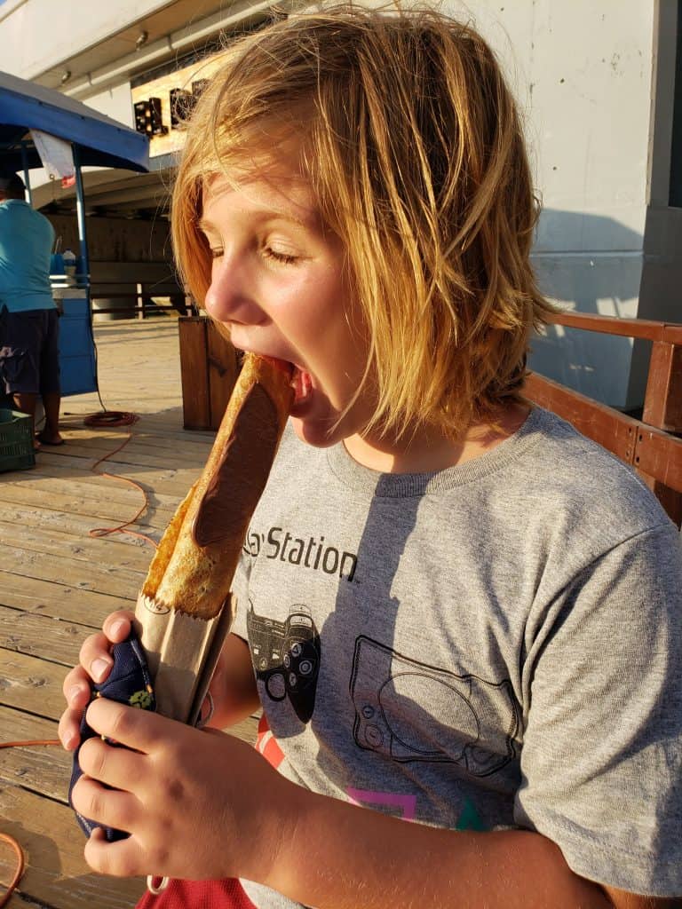 blond boy about to bite into chocolate covered marquesita
