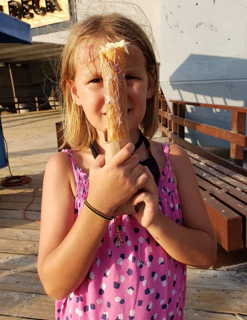 blonde girl in pink with waffle cone held up in front of her face