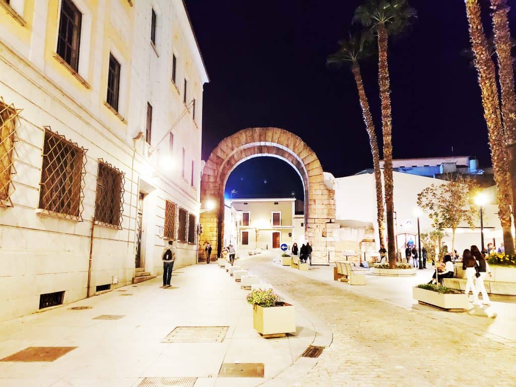 street scene at night, large Roman arch focal point