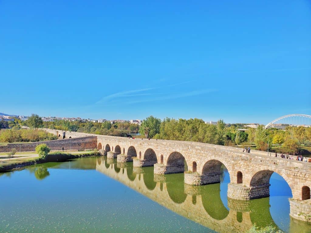Arched Roman bridge over river, perfect reflection
