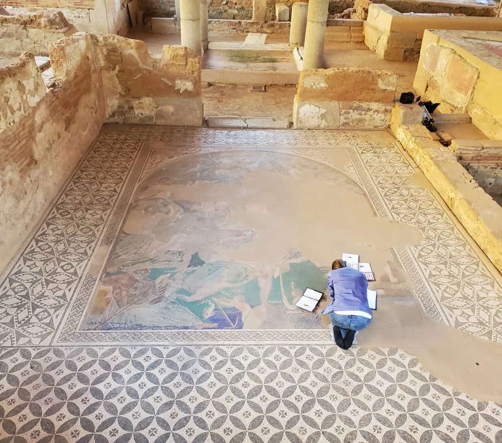 woman kneeling down working on ruined mosaic