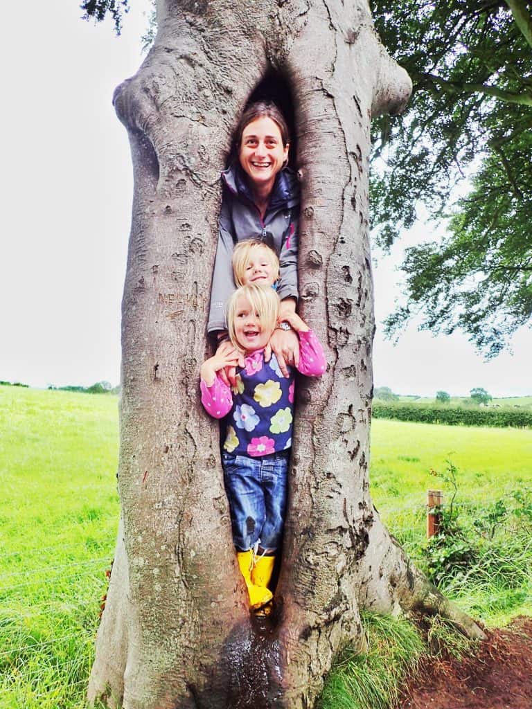 adult and two happy children standing in a split in a tree