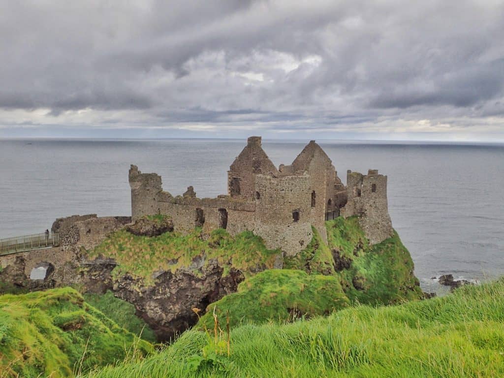 view of ruined castle on green cliff top. very grey sky