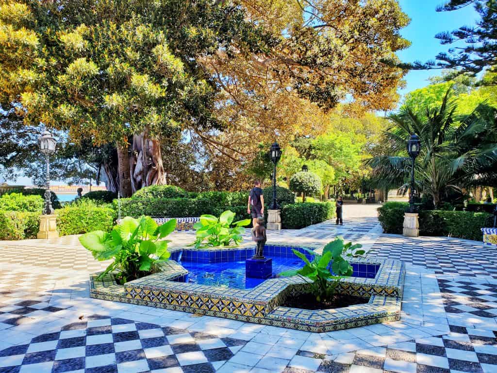 black and white tiled floor, deep blue fountain surrounded be trees