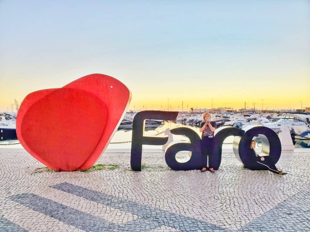Red heart next to FARO letters, kids with letters and small marina behind