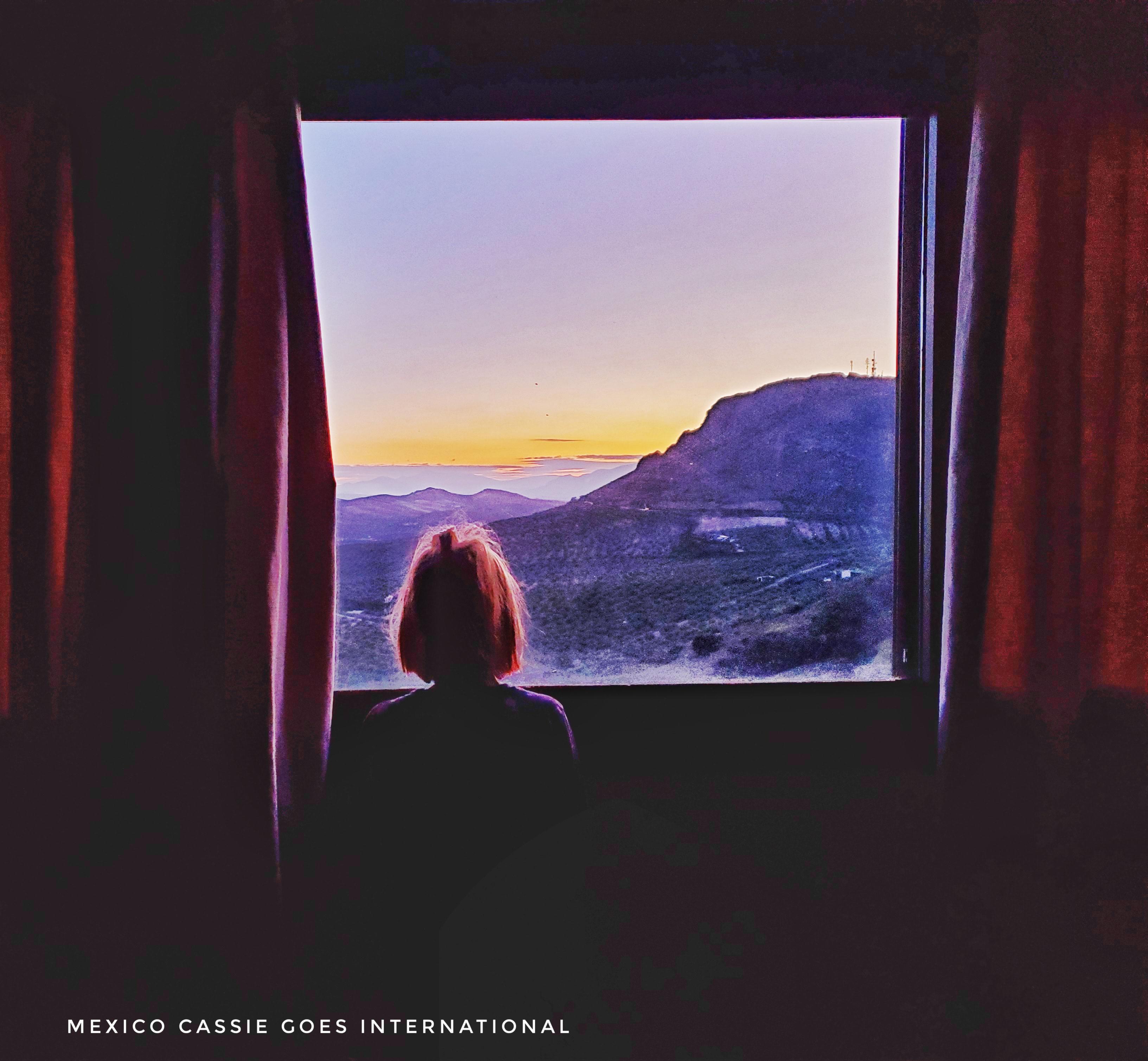 girl looking out of hotel window at dawn