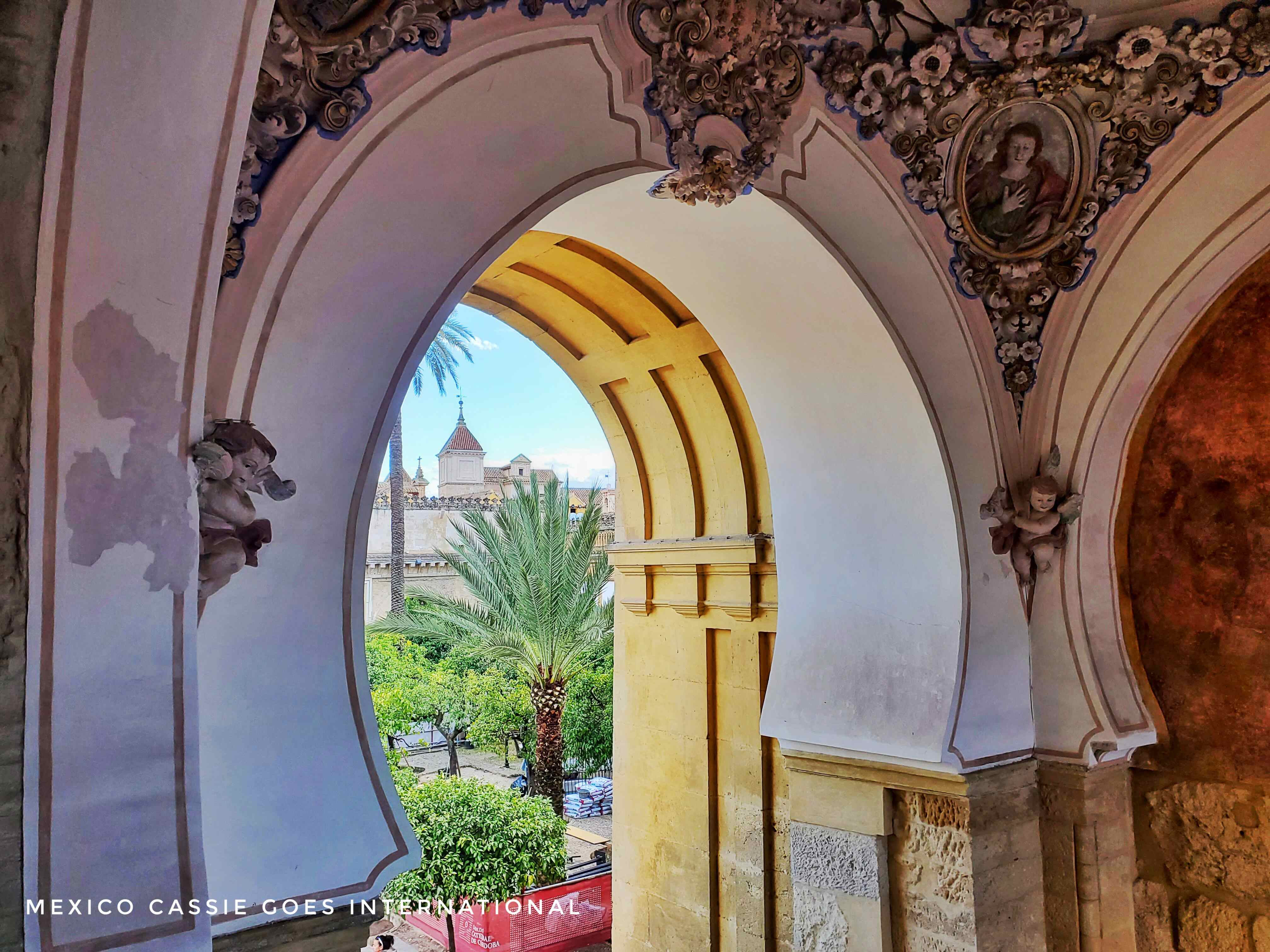 view through Islamic style arch to palm trees and a stylised building