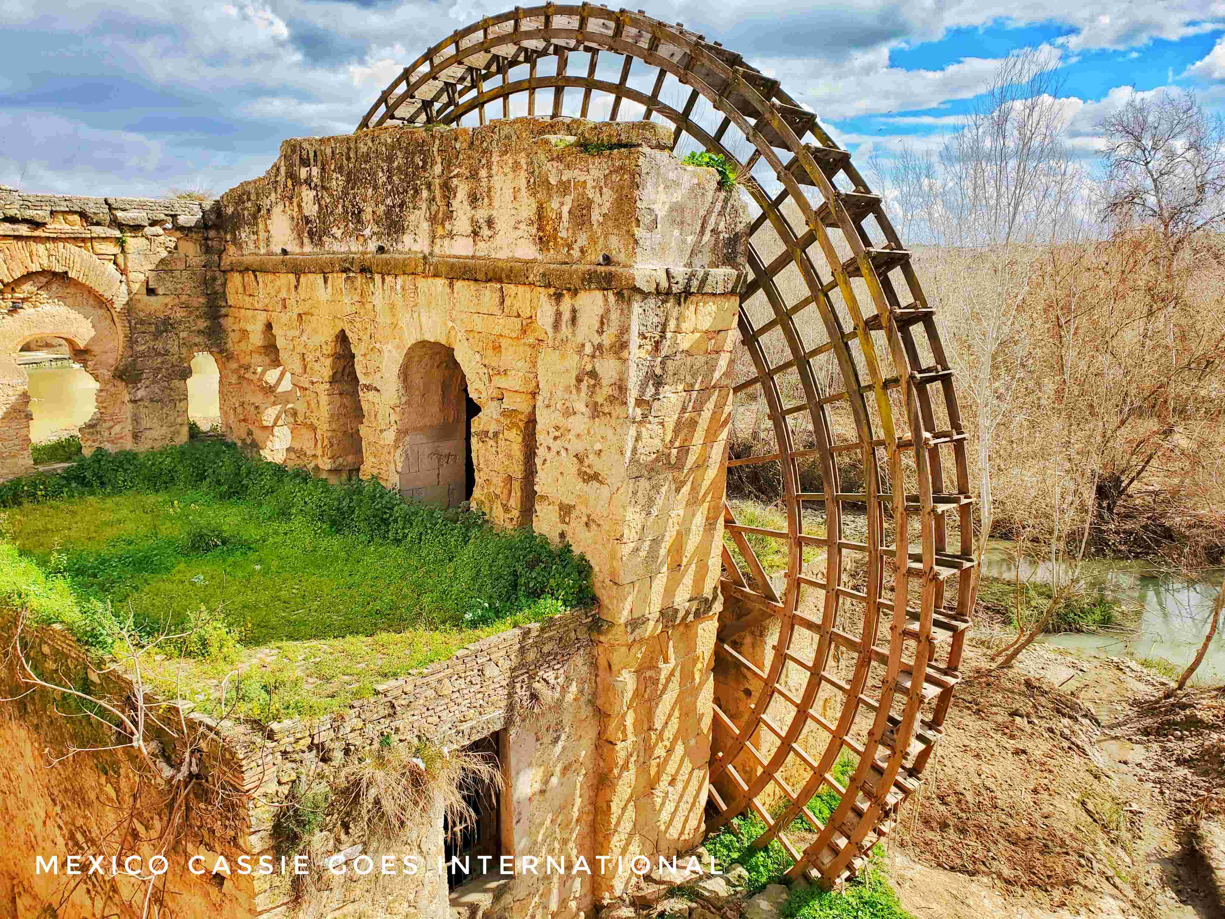 old wooden waterwheel attached to ruined arches