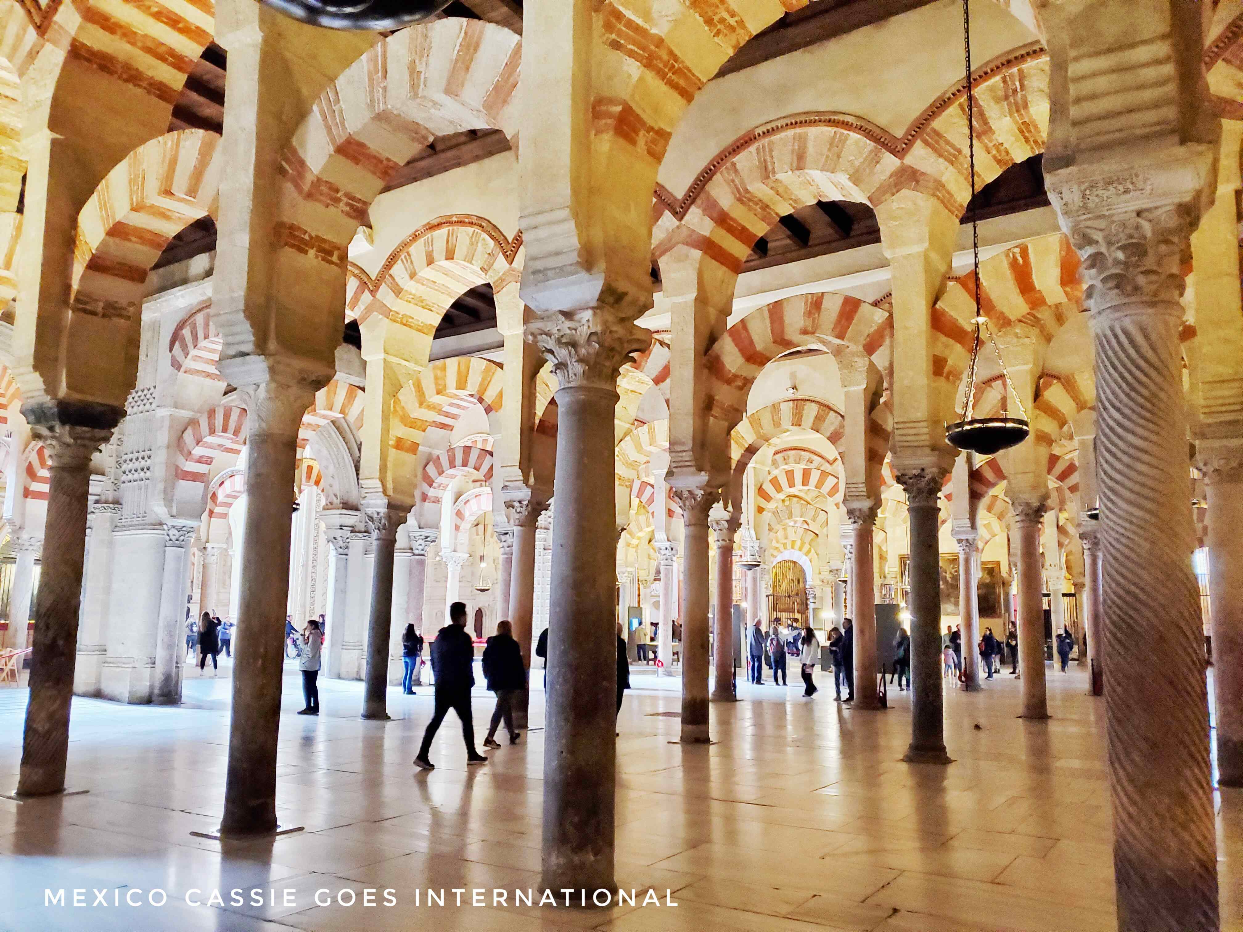 arches of the mezquita in cordoba, a few people walking around