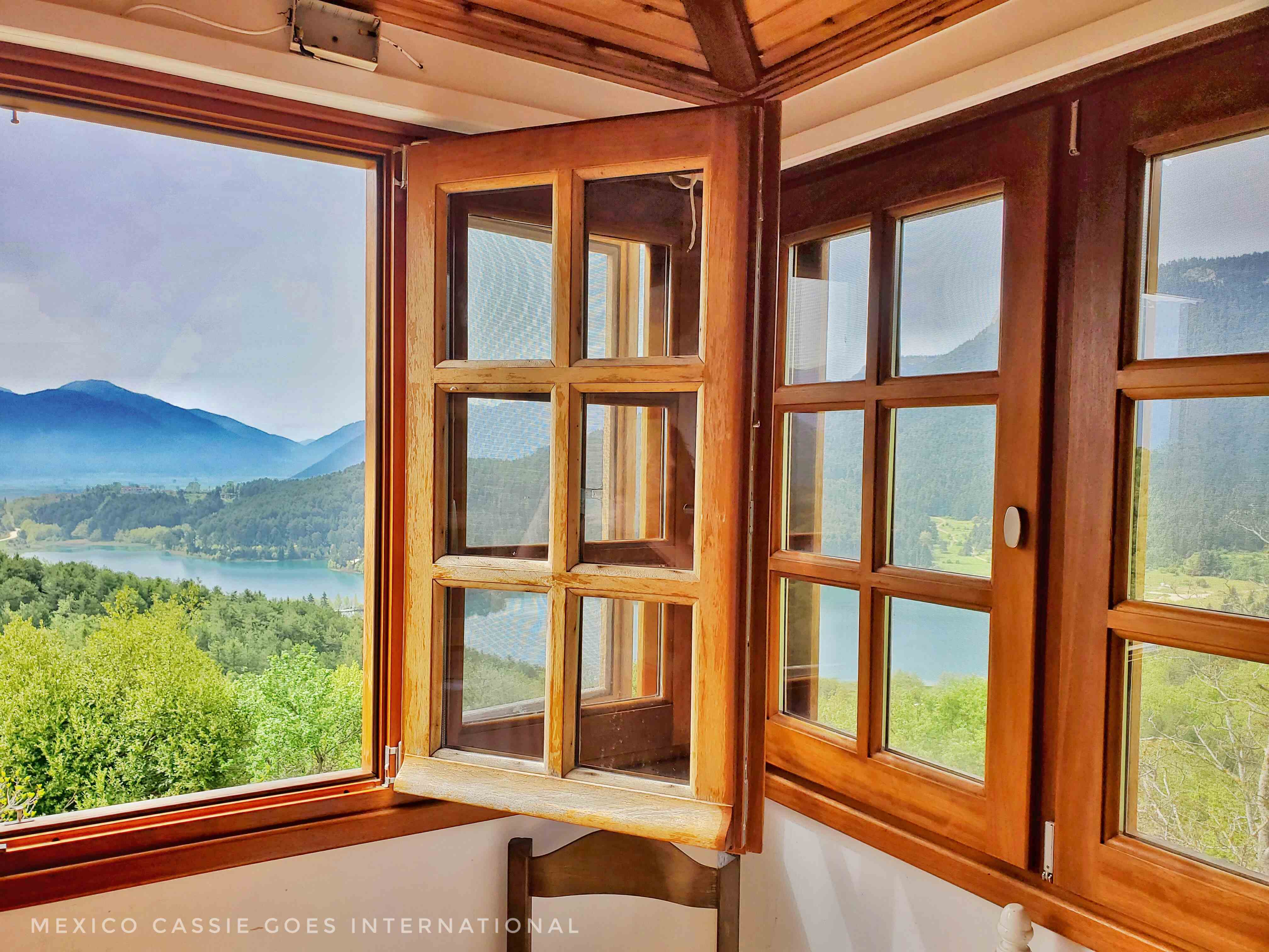 view out of wooden windows of trees and mountains and lake