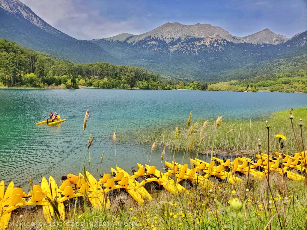 lake doxa - line of yellow pedalos on lake. mountains all around. one pair of people on a pedalo on lake
