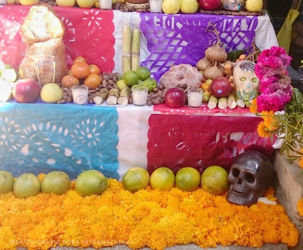 close up of an altar. orange flowers, papel picado, fruit